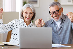 A man and woman excited looking at laptop